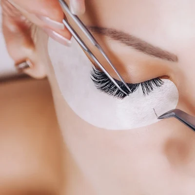 Eyelash extension procedure on a woman.