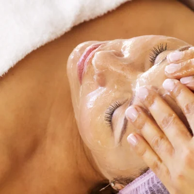 A woman in a spa getting a facial service.