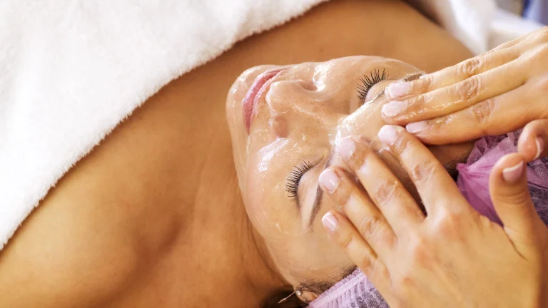 A woman in a spa getting a facial service.